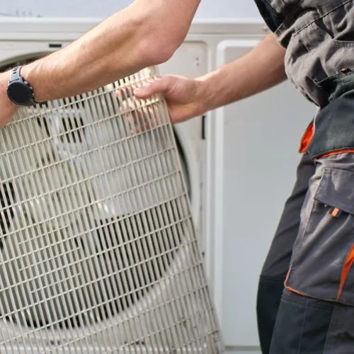 Technicien intervenant sur la grille d'une pompe à chaleur